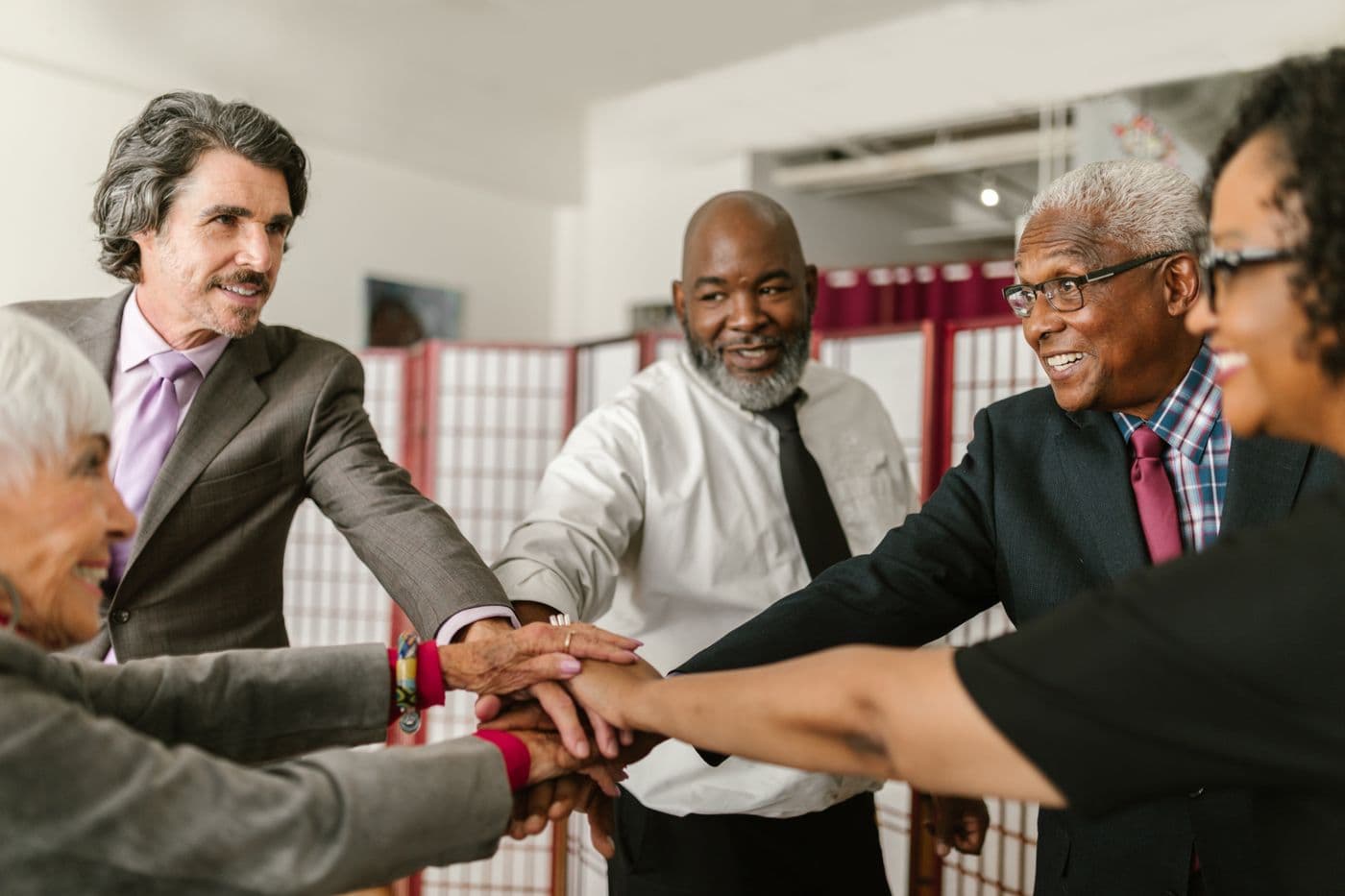 A small, diverse group of middle-aged and older men and women joining hands together